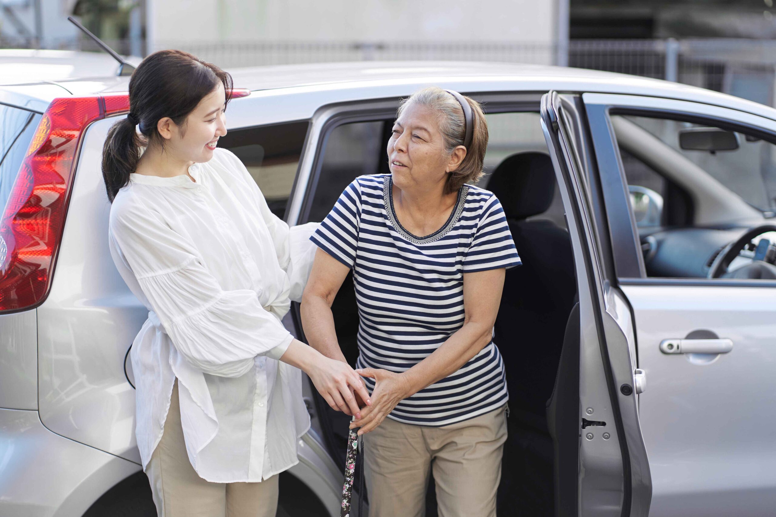 Caregiver assisting an elderly person as they get out of a car